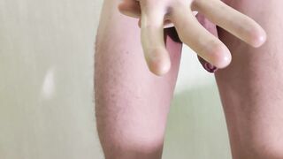 Pulling latex pants sheath on cock