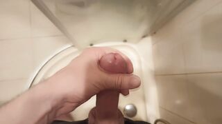 The guy masturbates his dick standing in the shower and cums