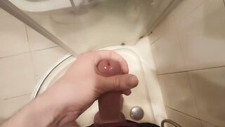 The guy masturbates his dick standing in the shower and cums